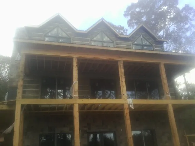 Dormers and porch framing on a large log home under construction — Roof Coating work by our crew in Jamestown