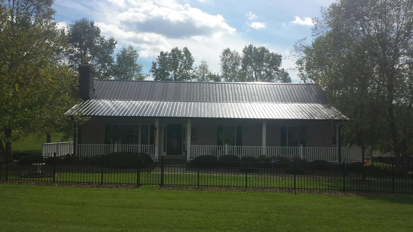 Gray metal roof on a brick ranch with a full width front porch — Gutter Guard Installation work by our crew in Jamestown
